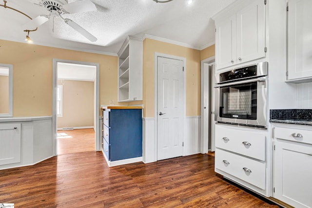 kitchen with a textured ceiling, a ceiling fan, stainless steel oven, white cabinetry, and dark wood-style floors