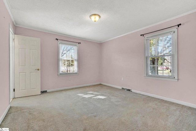 spare room with a textured ceiling, carpet floors, visible vents, and crown molding