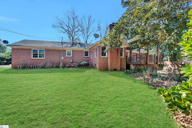 rear view of property featuring a yard, brick siding, crawl space, and a wooden deck