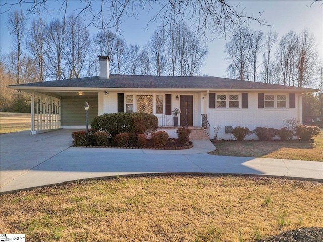 ranch-style house featuring covered porch, brick siding, driveway, a carport, and a front yard