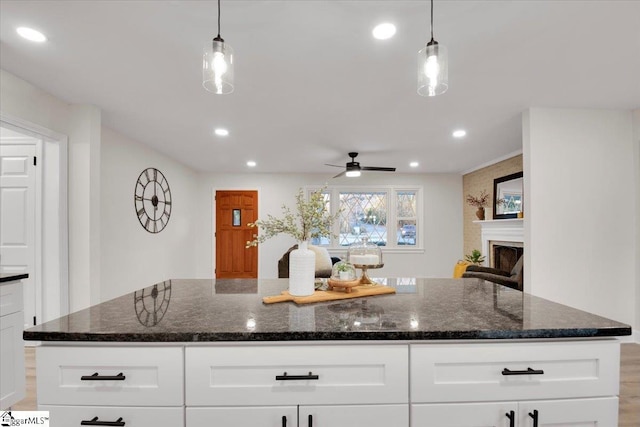 kitchen featuring dark stone counters, a fireplace, white cabinetry, and recessed lighting