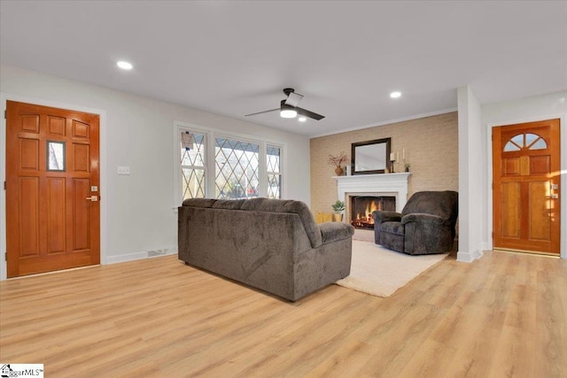 living area featuring a warm lit fireplace, wood finished floors, and baseboards