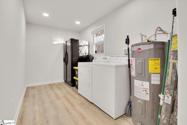 washroom featuring water heater, light wood-type flooring, laundry area, independent washer and dryer, and baseboards