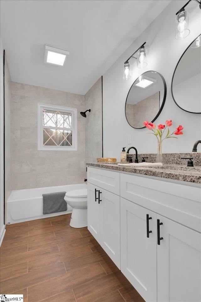 bathroom featuring toilet, shower / bathtub combination, wood finished floors, and vanity