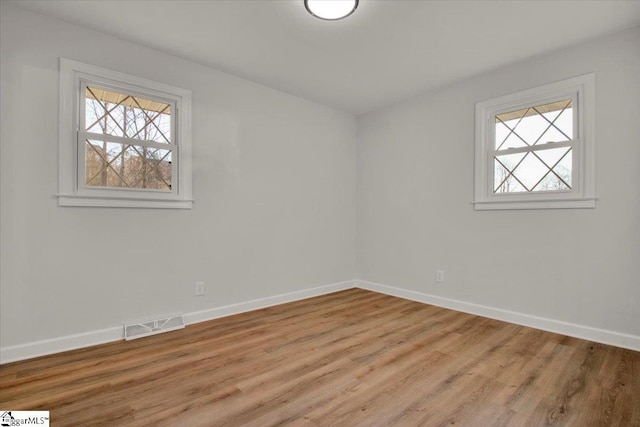 unfurnished room with visible vents, light wood-style flooring, and baseboards