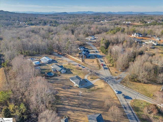 drone / aerial view with a wooded view and a mountain view