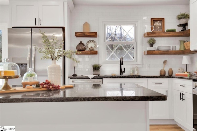 kitchen featuring stainless steel fridge, white cabinetry, backsplash, and a sink