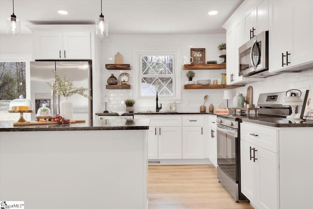 kitchen featuring stainless steel appliances, a sink, light wood-style flooring, and white cabinets