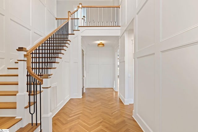 entrance foyer featuring visible vents, a decorative wall, stairway, and a high ceiling