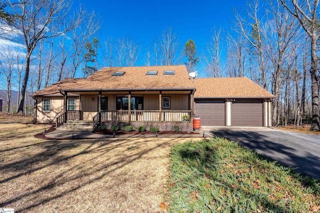 ranch-style home with a garage, a porch, aphalt driveway, and a front yard