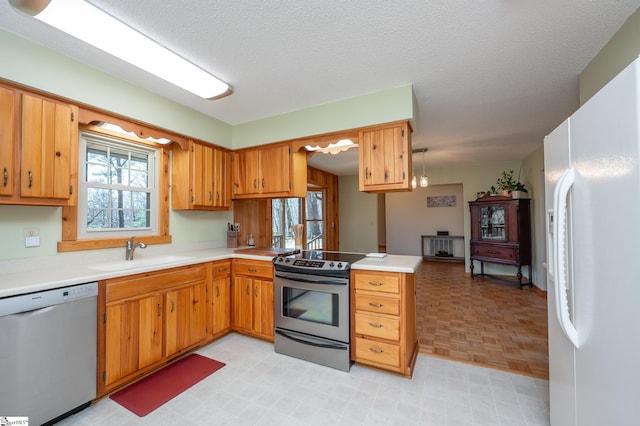 kitchen with stainless steel appliances, light countertops, a sink, and a peninsula