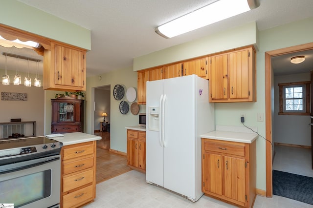 kitchen with light floors, light countertops, appliances with stainless steel finishes, a textured ceiling, and baseboards