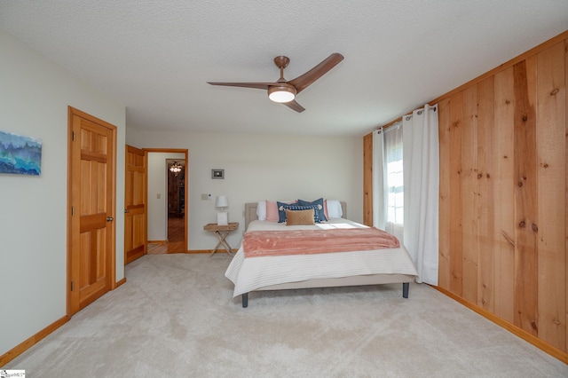 bedroom with light carpet, ceiling fan, a textured ceiling, and baseboards