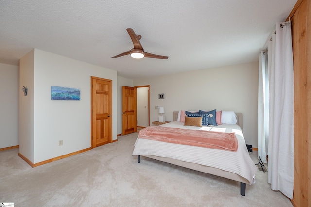 bedroom featuring light carpet, ceiling fan, a textured ceiling, and baseboards