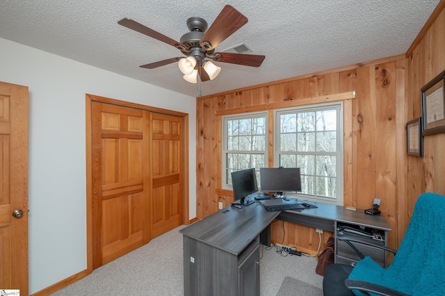 home office with a textured ceiling, carpet, a ceiling fan, and wooden walls