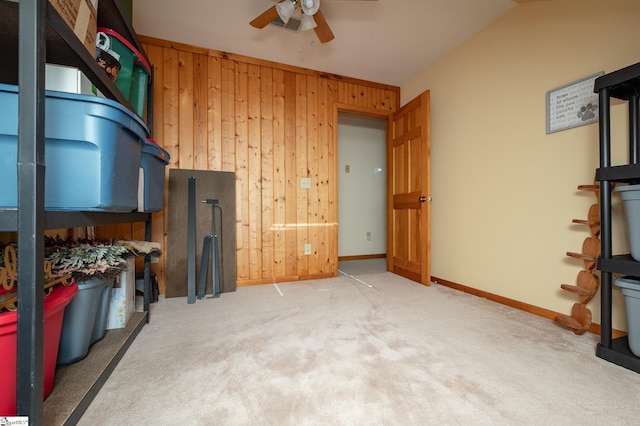 interior space with carpet flooring, ceiling fan, wooden walls, and baseboards