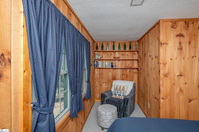 carpeted bedroom featuring wood walls, visible vents, and a textured ceiling