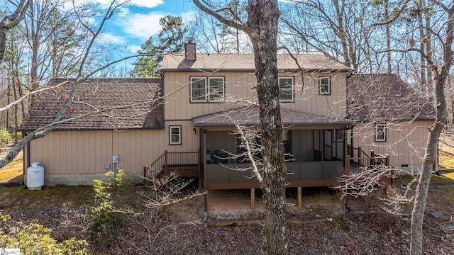 rear view of property with roof with shingles, a chimney, and a sunroom