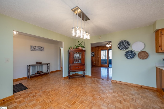 interior space with a textured ceiling, ceiling fan, and baseboards