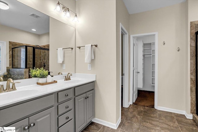 bathroom featuring a spacious closet, visible vents, a shower stall, and a sink