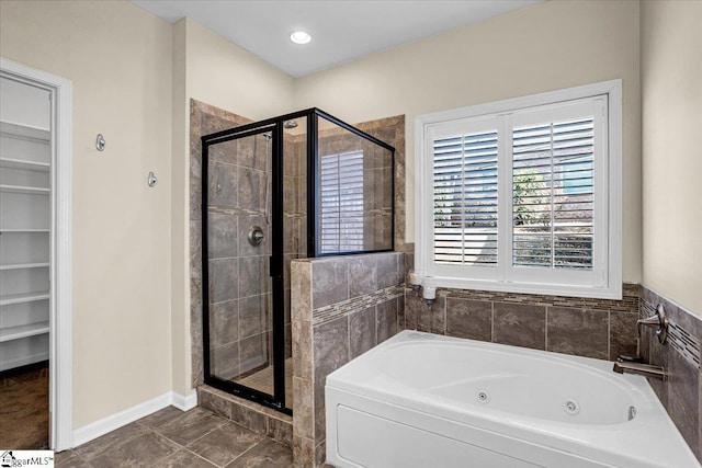 bathroom featuring a tub with jets, baseboards, recessed lighting, a shower stall, and a walk in closet