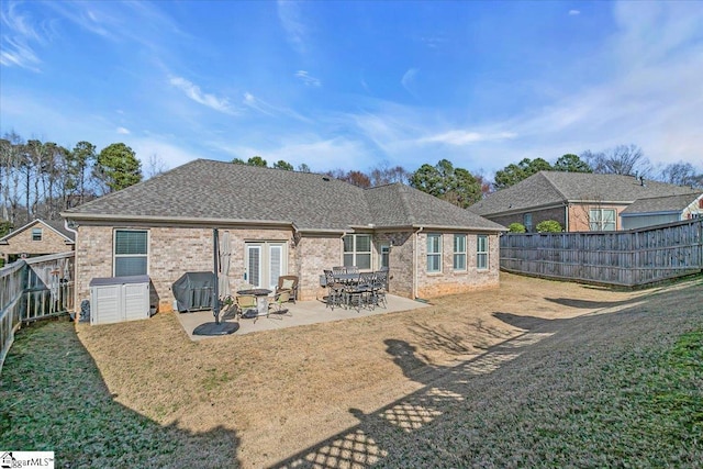 back of house with brick siding, a shingled roof, and a fenced backyard