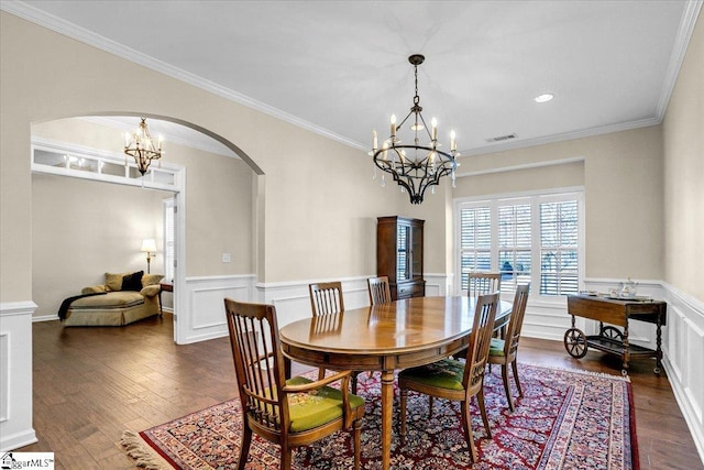 dining area featuring a notable chandelier, dark wood-style floors, arched walkways, and wainscoting