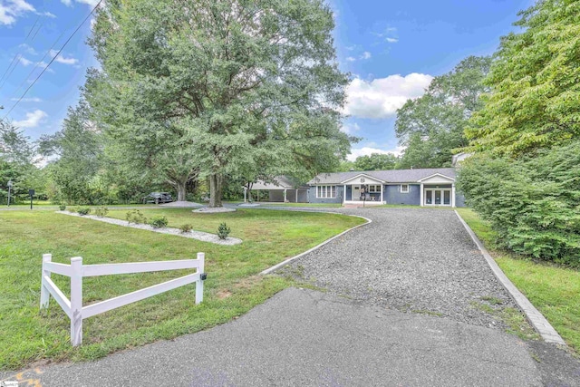 ranch-style home with driveway, fence, and a front yard