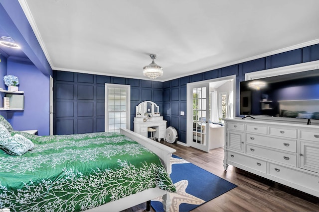 bedroom with dark wood finished floors, a decorative wall, crown molding, and french doors