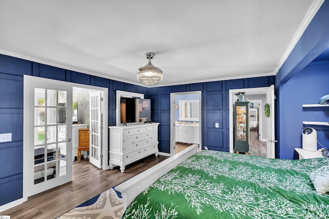 bedroom featuring dark wood finished floors, french doors, crown molding, and a decorative wall