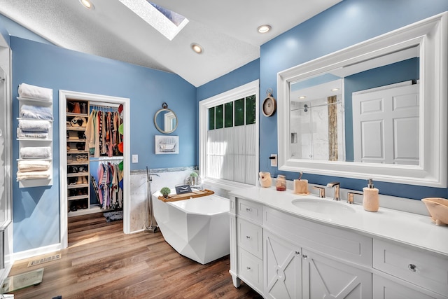 full bathroom featuring recessed lighting, wood finished floors, vanity, a soaking tub, and a stall shower