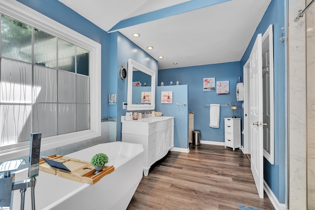 full bathroom featuring recessed lighting, vanity, wood finished floors, a freestanding tub, and baseboards