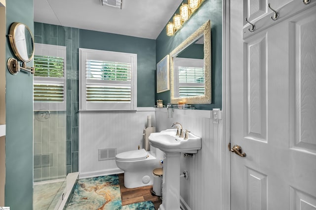 full bath featuring a stall shower, visible vents, toilet, a wainscoted wall, and wood finished floors