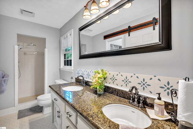 bathroom featuring toilet, visible vents, a sink, and tiled shower