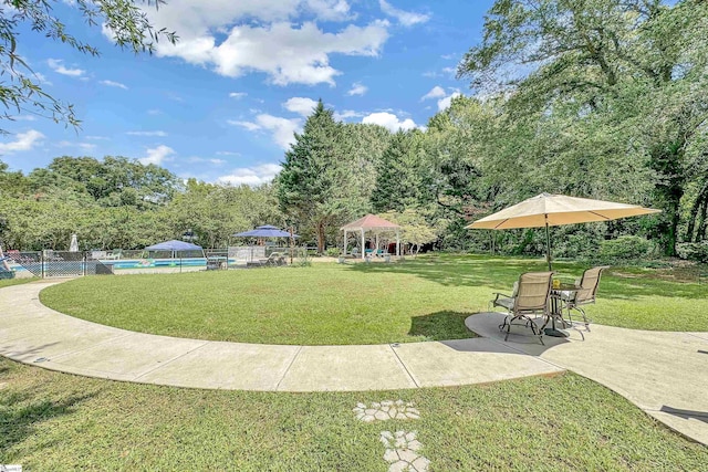 surrounding community with a gazebo, a lawn, a swimming pool, and fence