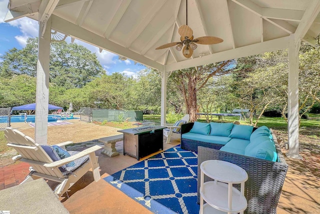 view of patio featuring a ceiling fan, an outdoor living space with a fire pit, and an outdoor pool