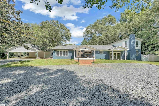 single story home featuring gravel driveway, a chimney, fence, and a front lawn