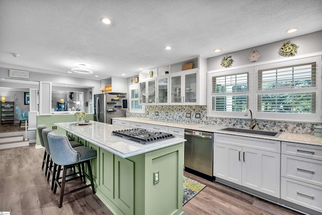 kitchen featuring white cabinetry, appliances with stainless steel finishes, a sink, and a center island