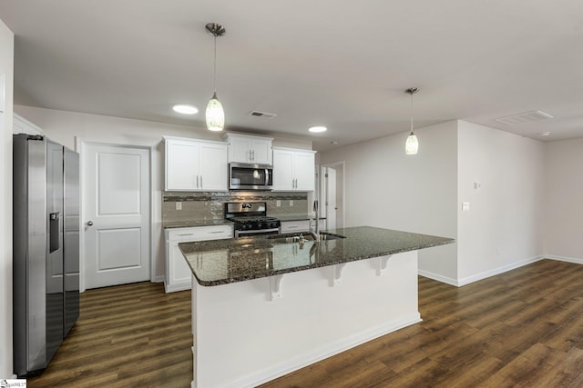 kitchen with dark wood-style flooring, stainless steel appliances, tasteful backsplash, visible vents, and white cabinets