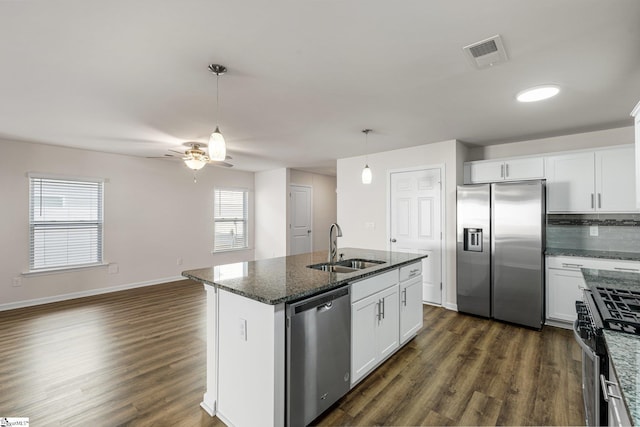 kitchen with dark wood-style floors, stainless steel appliances, visible vents, a sink, and dark stone counters