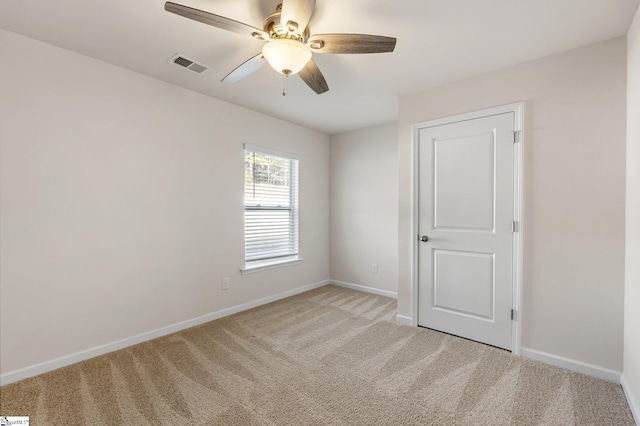 empty room featuring baseboards, visible vents, a ceiling fan, and light colored carpet