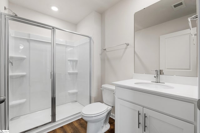 bathroom featuring toilet, wood finished floors, visible vents, vanity, and a stall shower