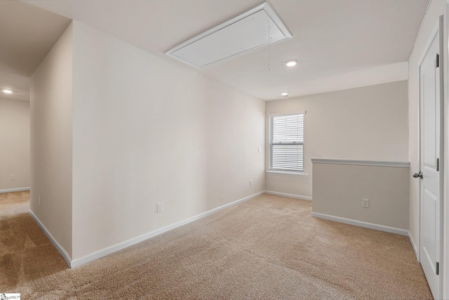 empty room featuring light carpet, recessed lighting, attic access, and baseboards