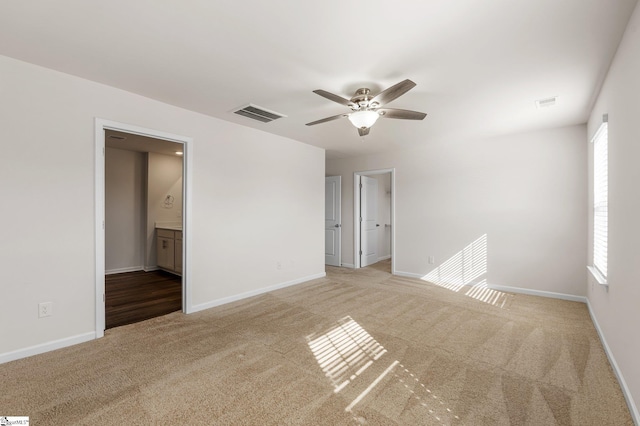 spare room with baseboards, visible vents, and light colored carpet