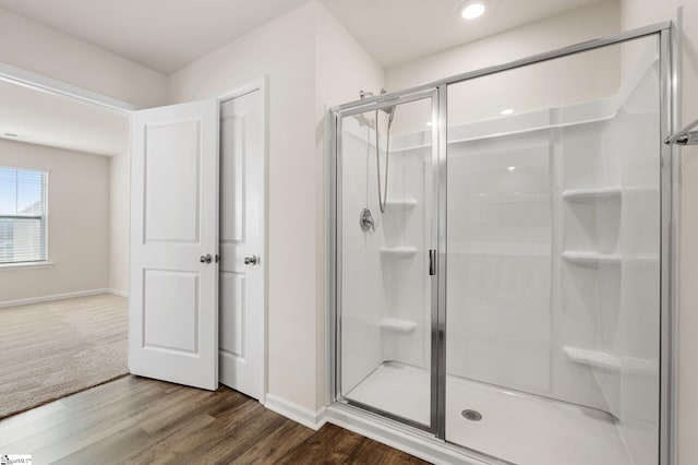 bathroom with a shower stall, baseboards, and wood finished floors