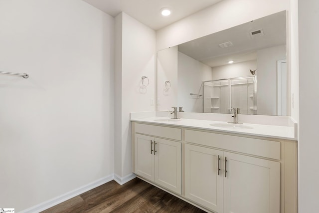 full bathroom featuring double vanity, a stall shower, visible vents, wood finished floors, and a sink