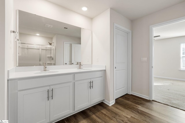 full bathroom with visible vents, a sink, a shower stall, and wood finished floors