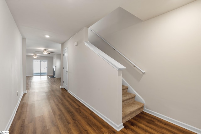 corridor featuring dark wood finished floors, baseboards, and stairs