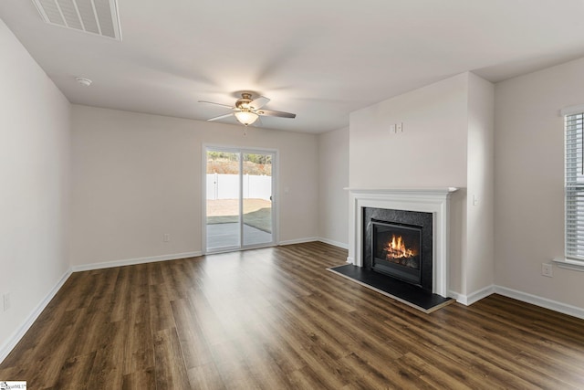 unfurnished living room featuring dark wood-style floors, a fireplace, visible vents, a ceiling fan, and baseboards