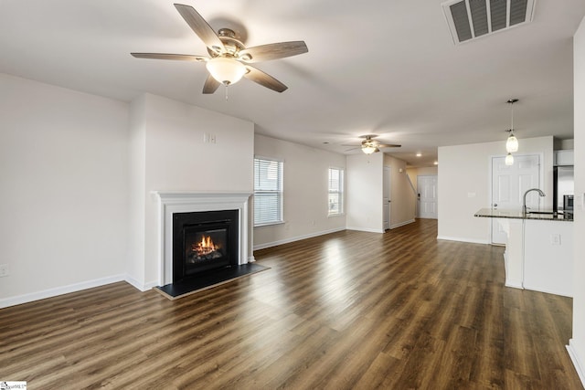 unfurnished living room with dark wood-type flooring, visible vents, and baseboards